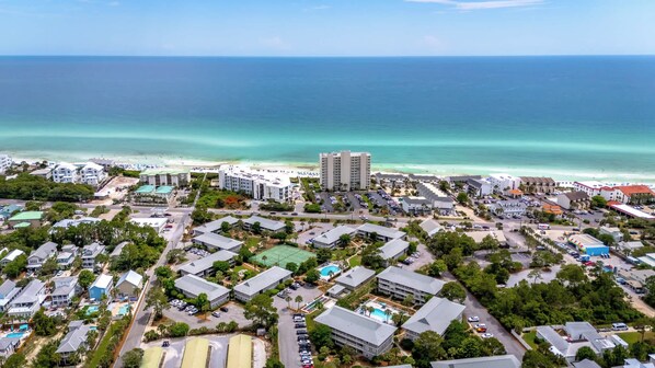 A coastal resort area with beachfront hotels, a large hotel building, and a clear view of the ocean. - 30A Condo · Walk to Beach · 2 Pools + Tennis (Santa Rosa Beach)
