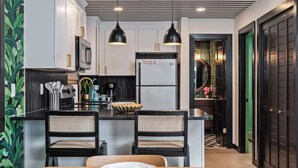 A modern kitchen with white cabinets, black pendant lights, and a central island with two chairs. - 30A Condo · Walk to Beach · 2 Pools + Tennis (Santa Rosa Beach)
