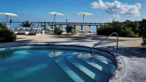 A pool with a view of a bridge and umbrellas in the background. - Jacuzzi Suite Overlooking the Sea @Islamorada - Iguana Suite (Islamorada)