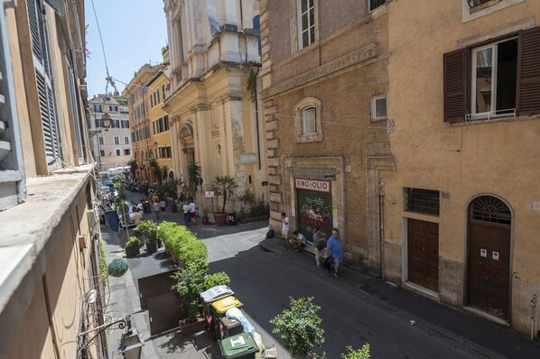 A narrow street with buildings on both sides, a few people walking, and a parked vehicle. - Elegant Roman Retreat by Campo de Fiori (Roma)