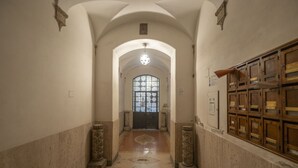 A hallway with an arched ceiling, a chandelier, a wooden cabinet with drawers, and a door with a glass window. - Elegant Roman Retreat by Campo de Fiori (Roma)
