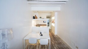 A modern, minimalist dining area with a white table and chairs, a clear glass partition, and a wooden floor. - Elegant Roman Retreat by Campo de Fiori (Roma)