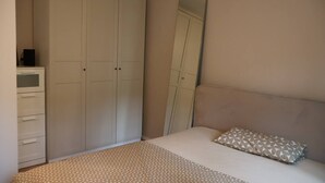 A bedroom with a bed, a dresser, a wardrobe, and a mirror.