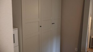 A white closet with two doors and a small cabinet to the left.