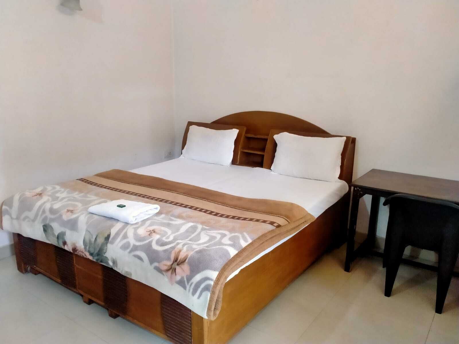 A neatly made bed with a floral bedspread and a folded towel on the side.