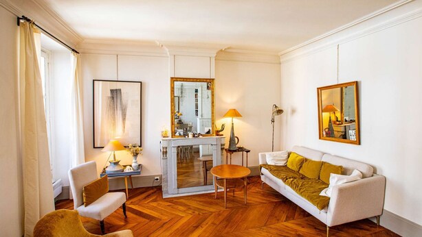 Una sala de estar bien iluminada con un sofá, un sillón y un comedor con mesa y sillas.