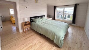 Una camera da letto con un letto, un comodino, una finestra con vista e un pavimento in legno.