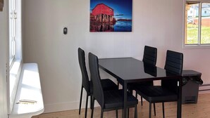 Zona pranzo con tavolo e sedie, un quadro appeso al muro e una finestra.