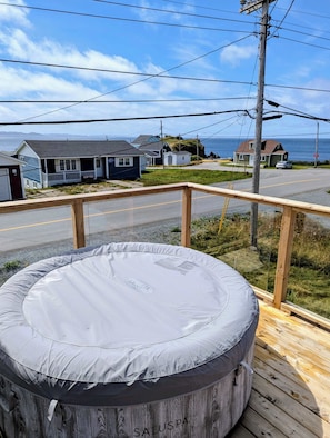 Eine Holzterrasse mit Whirlpool, Blick auf Häuser und eine Straße.