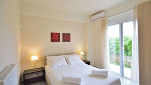 A hotel room with a bed, two bedside lamps, a window with curtains, and two wall-mounted artworks. - Villa Nopigia Mare, Kissamos Chania (Chania)