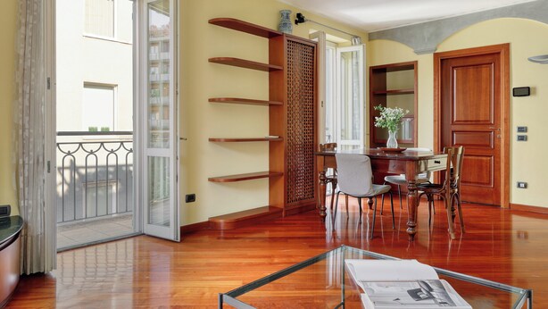 A spacious living area with a wooden floor, a glass coffee table, and a dining table with chairs. - Delightful 2BR flat near Navigli (Milan)