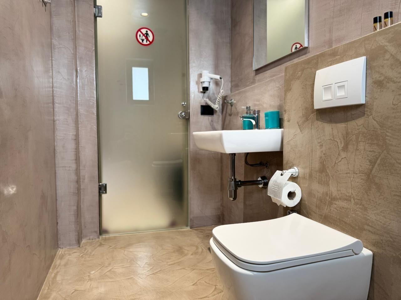 Un baño con inodoro, lavamanos y zona de ducha.