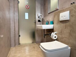 Un baño con inodoro, lavamanos y zona de ducha.