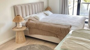 Ein ordentlich eingerichtetes Schlafzimmer mit einem Bett, einer Nachttischlampe und einem kleinen Holztisch.