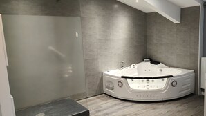 A modern bathroom with a freestanding bathtub, a shower area, and a toilet.