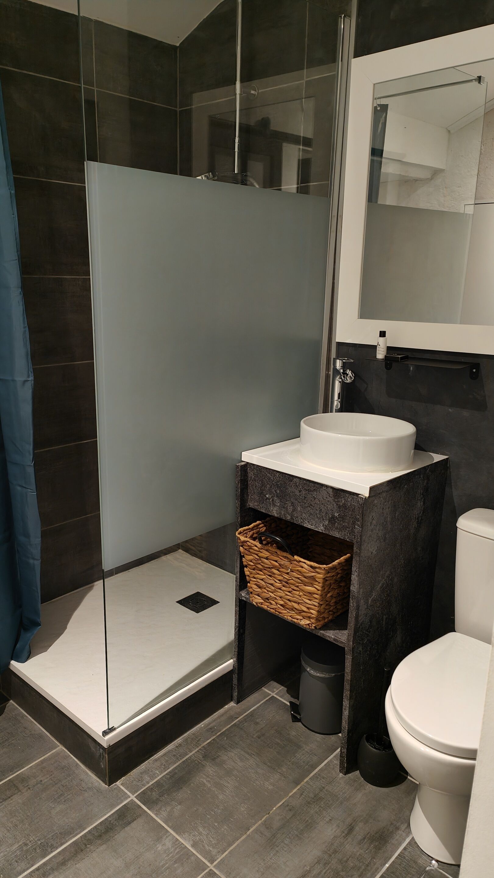Ein modernes Badezimmer mit Duschkabine aus Glas, einem weißen Waschbecken und einer Toilette.