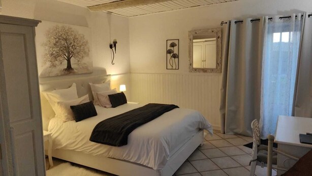 A neatly arranged bedroom with a bed, bedside table, and a chair.