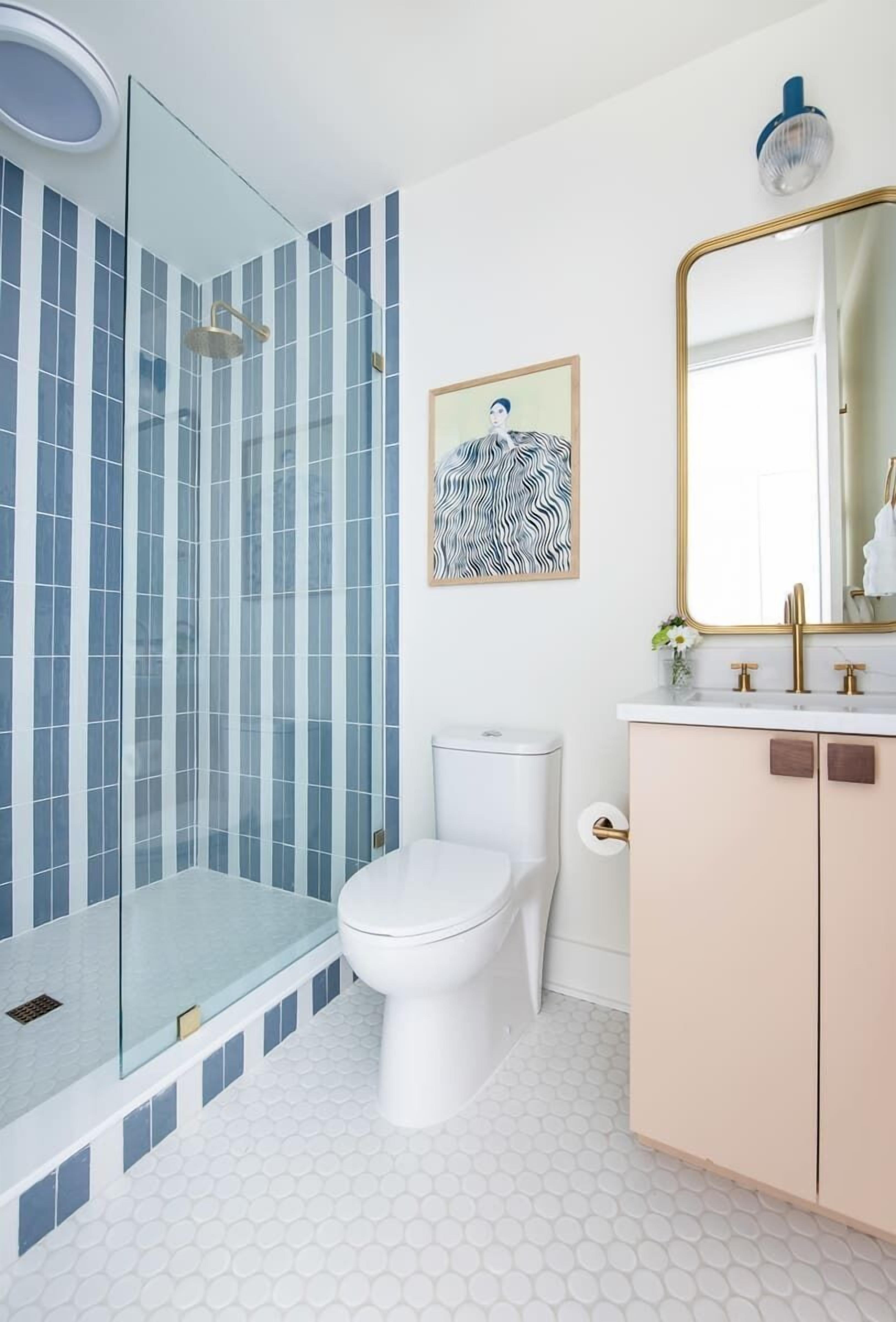 Une salle de bain avec une douche à parois de verre, des toilettes, un lavabo avec un miroir et un mur décoré d’un motif.