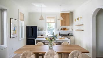 A modern kitchen with a wooden dining table, black refrigerator, and white cabinetry.
