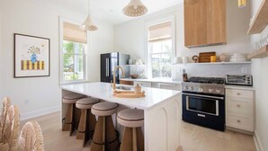 A modern kitchen with a central island, black appliances, and a wooden upper cabinet.