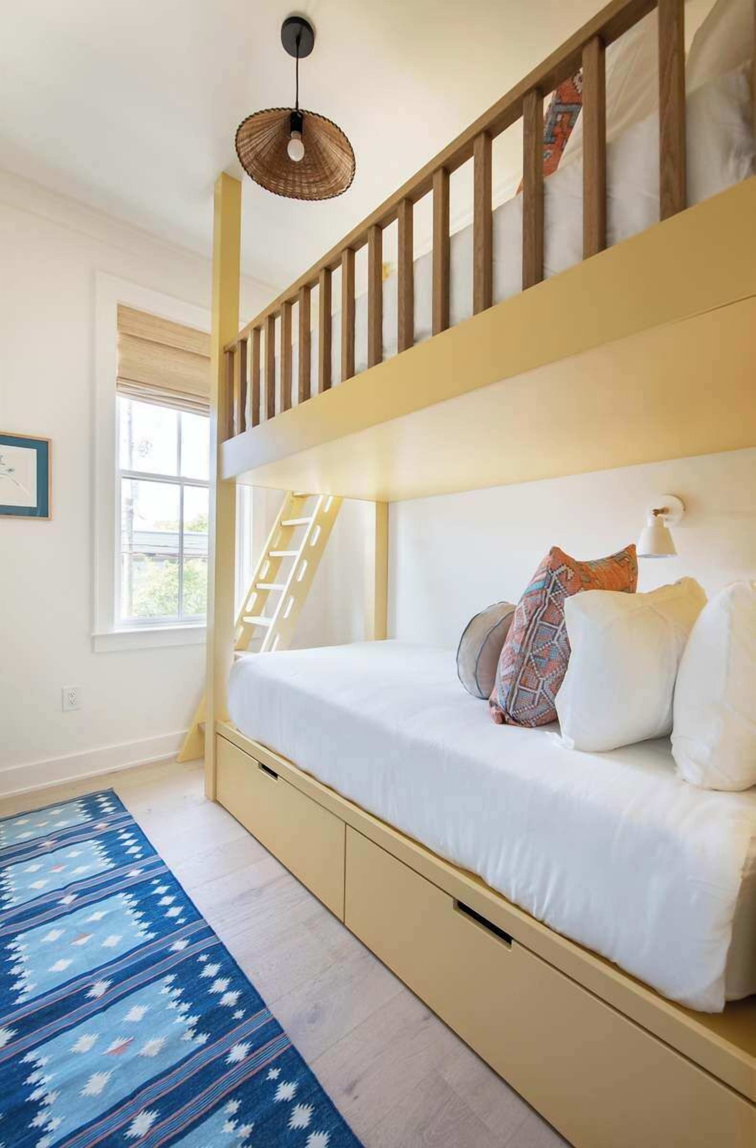 A bunk bed with a ladder, white bedding, and a patterned rug.