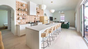 A modern kitchen with a central island, bar stools, and pendant lighting.