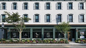 A two-story building with a row of windows on the upper floor and a ground-floor storefront with signage indicating availability.