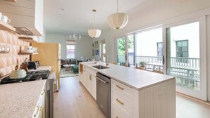 A modern kitchen with a central island, a dining area with a view, and a balcony with outdoor seating.