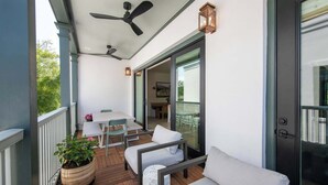 A covered porch with a table and chairs, a sofa, a potted plant, and a sliding glass door leading to an outdoor area.