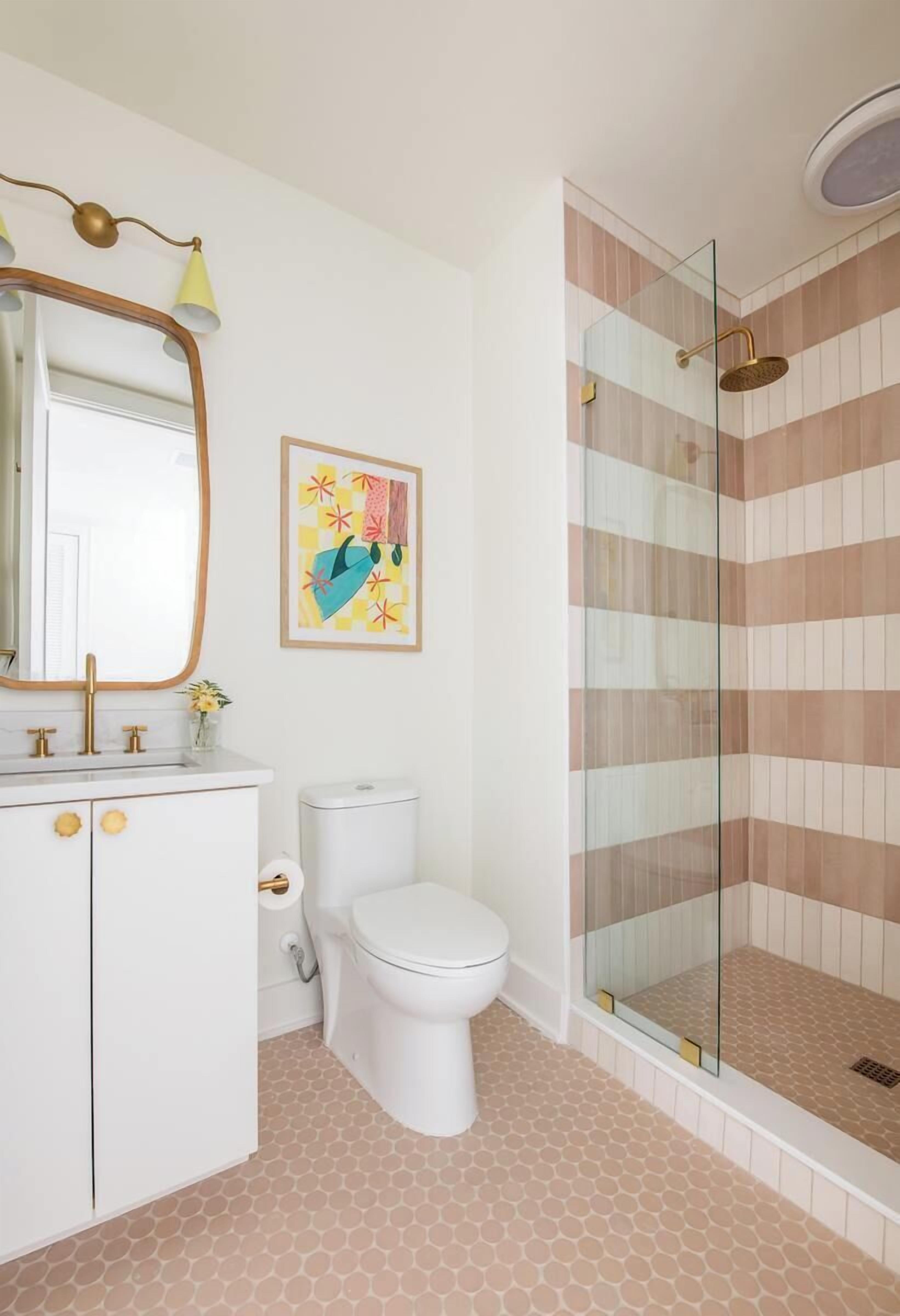 Un baño con lavamanos blanco, inodoro y cabina de ducha con mampara de vidrio.