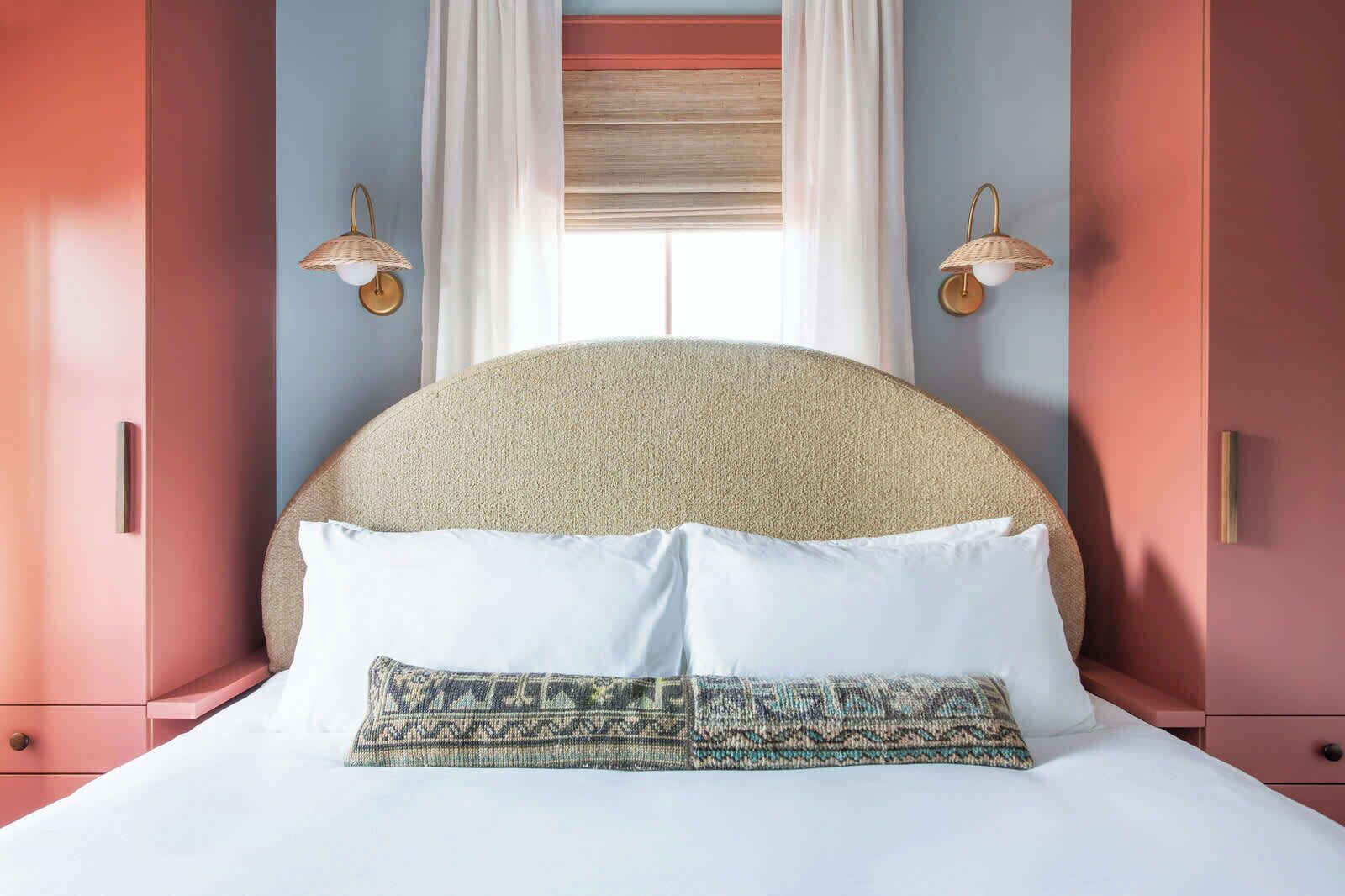 Ein Bett mit einem strukturierten Kopfteil, weißen Kissen und einer gemusterten Decke.