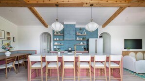 Une cuisine moderne avec des carreaux bleus, des poutres en bois et un îlot central doté de chaises.