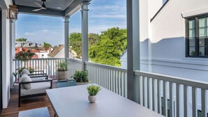 Un balcon couvert, doté d’une table et de sièges, donnant sur un quartier résidentiel.