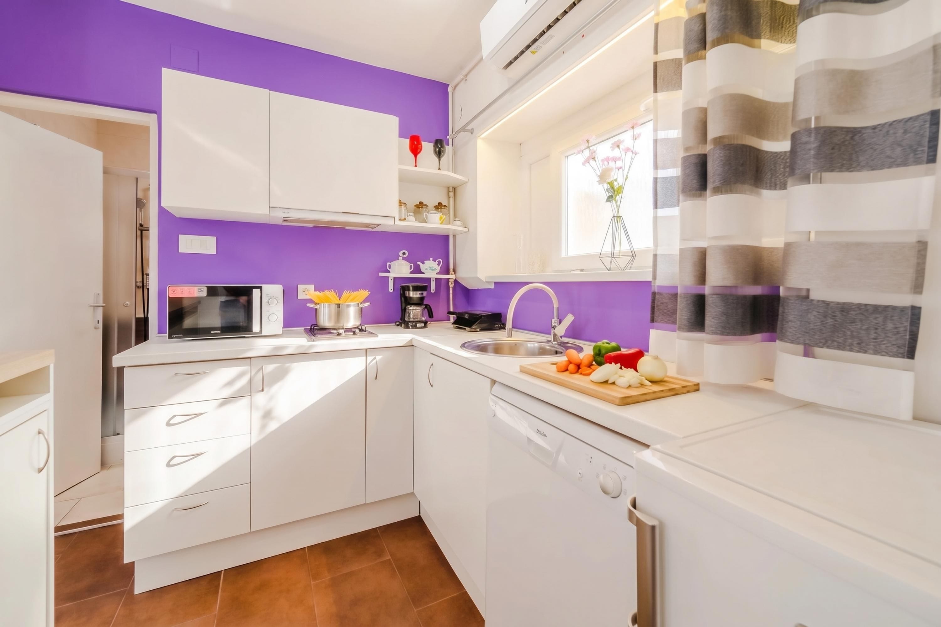 A compact kitchen with white cabinets, a microwave, a coffee maker, and a sink.