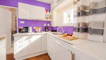 A compact kitchen with white cabinets, a microwave, a coffee maker, and a sink.