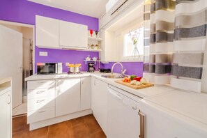 A compact kitchen with white cabinets, a microwave, a coffee maker, and a sink. - Charming Downtown Studio (Zagreb)