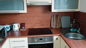 Una cocina compacta equipada con microondas, hervidor y horno empotrado.