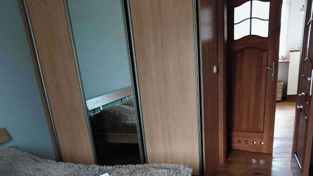 Un dormitorio con una cama, una alfombra gris y mullida, y una alfombra en el suelo con estampado blanco y negro.