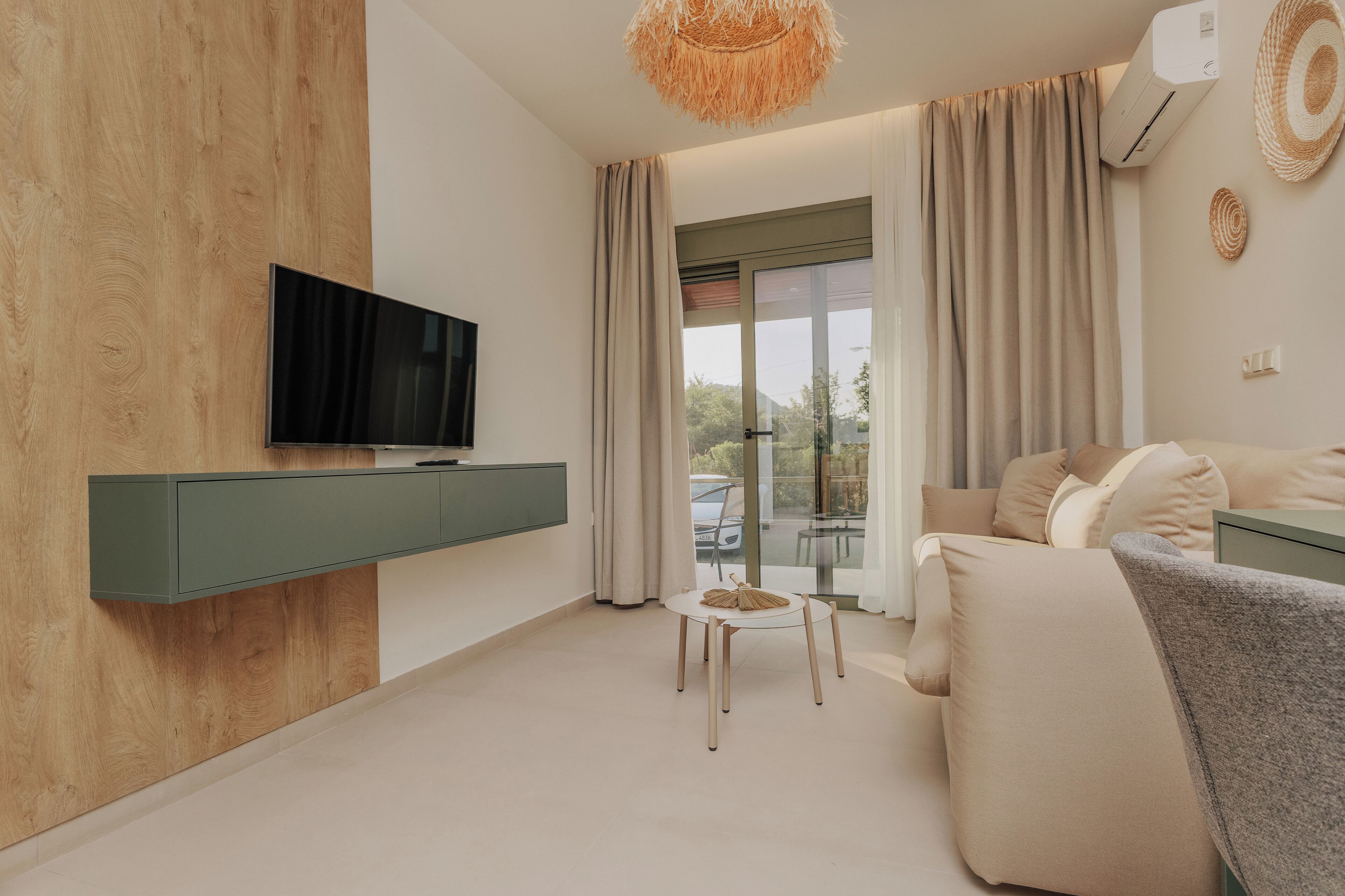 Una sala de estar moderna con televisor de pantalla plana, una mesa redonda y un sofá.