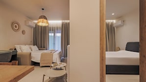 Moderni hotellihuone, jossa on sänky, sohva, ruokapöytä ja pieni sivupöytä.