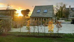 A stone house with a sloped roof and two skylights, surrounded by a well-maintained lawn and trees. - Idyllic secluded hideaway with countryside views (Hailey)