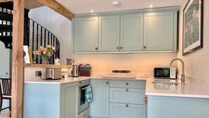 A compact kitchen with light blue cabinets, a microwave, a toaster, and a sink. - Idyllic secluded hideaway with countryside views (Hailey)
