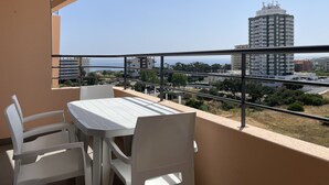 Ein Balkon mit Tisch und Stühlen mit Blick auf eine Stadtlandschaft mit Gebäuden und blauem Himmel.