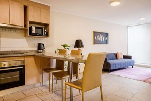 A modern kitchen with a microwave, stove, and seating area with chairs and a table.