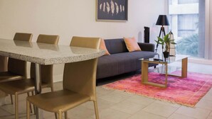 A modern living room with a dining table, sofa, and a large window. - Modern 1BR Gem in City Center | Steps to Metro (Unknown)