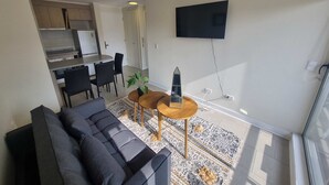 Ein modernes Wohnzimmer mit einer Couch, einem Couchtisch und einem an der Wand befestigten Fernseher.