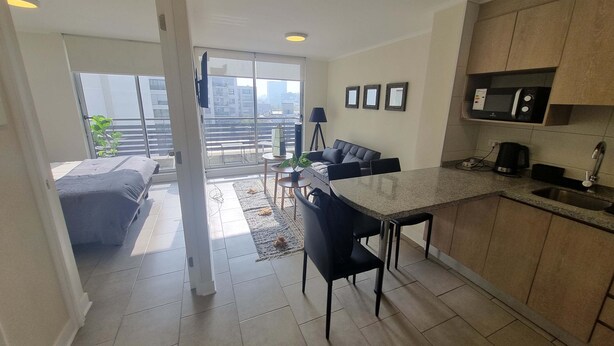 Eine moderne Wohnung mit Küche, Essbereich und einem Balkon mit Blick auf die Stadt.