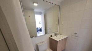 Ein Badezimmer mit Toilette, Waschbecken, Spiegel und Dusche.