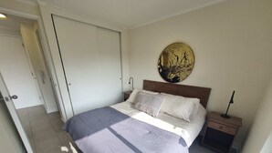 Ein Schlafzimmer mit Bett, Nachttisch, Wandlampe und einer Tür.