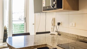 A kitchen with a granite countertop, a microwave, a stove, and wooden cabinets. - Central Chic 1BR Steps from Metro & Attractions (Santiago)